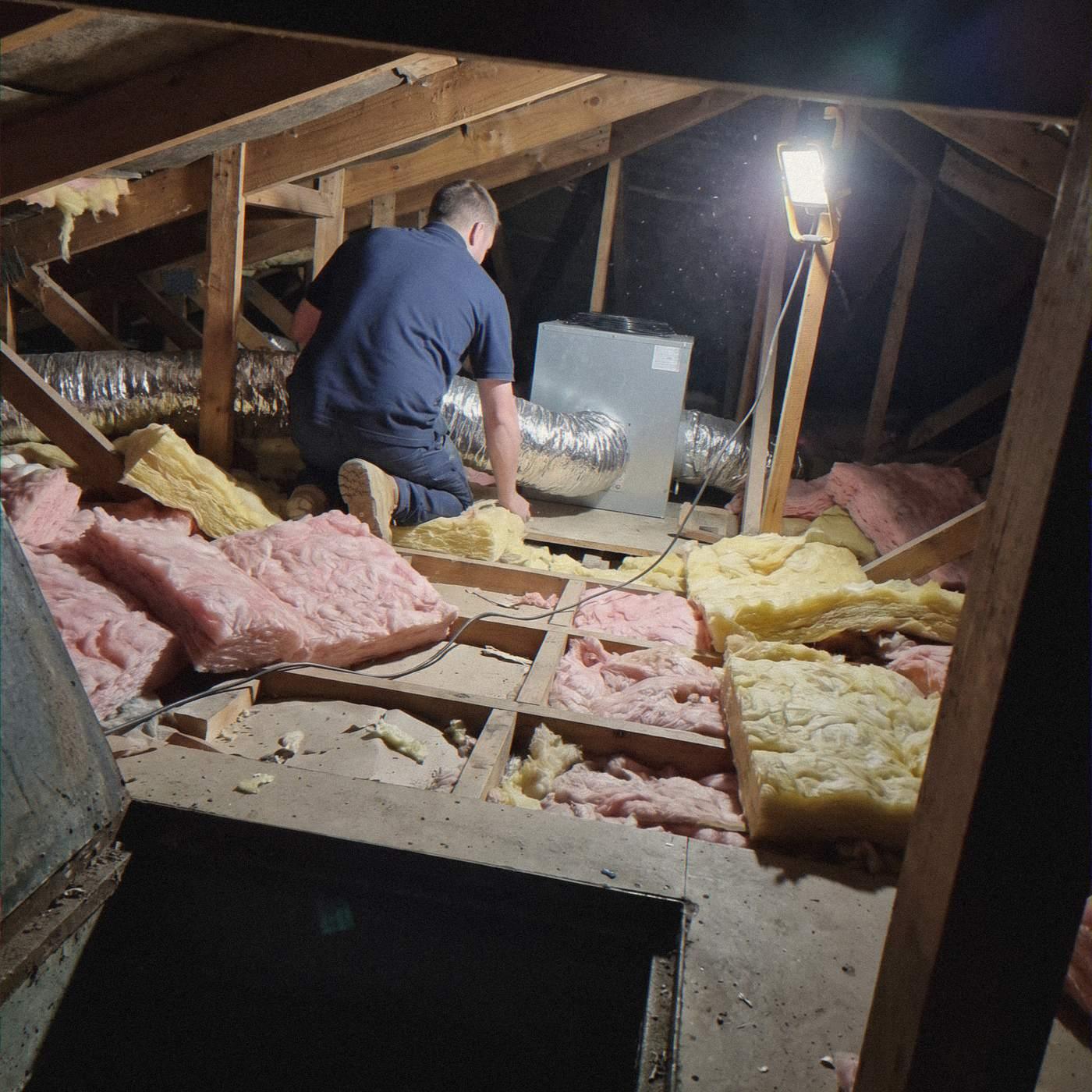 Installer connecting flexible ducting to a fan-coil unit in a roof cavity