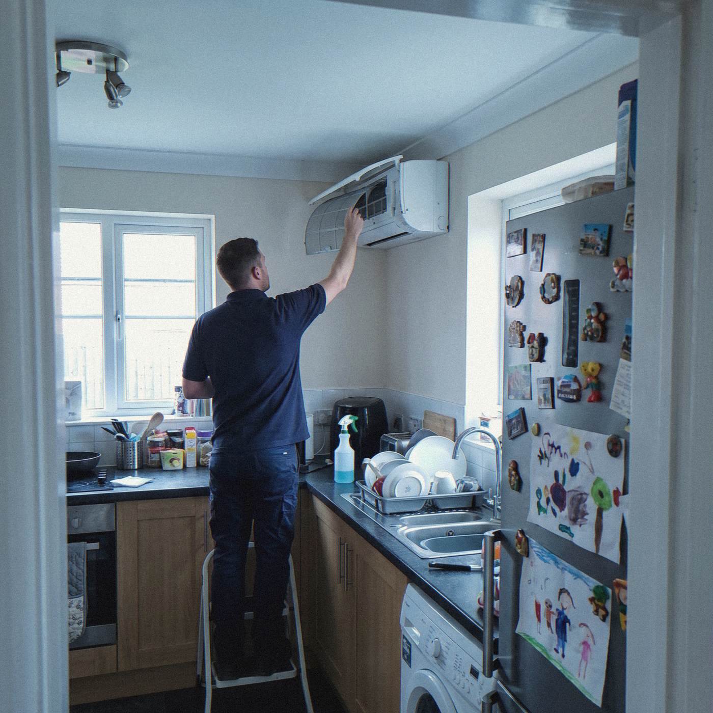 Installer removing the filters from a hi-wall heat pump in a family kitchen